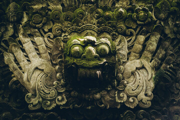 Close up shot of stone face statue in monkey forest. Balinese sculpture architecture in sacred...