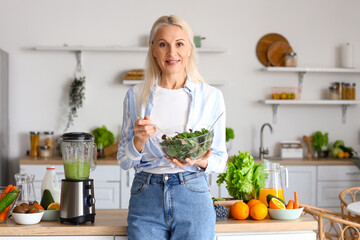 Mature woman with bowl of vegetable salad in kitchen