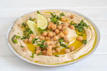Chickpeas, fresh lime, mint on hummus plate. Mediterranean food.
