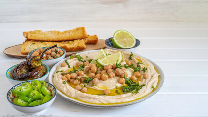 Chickpeas, fresh lime and mint over freshly prepared hummus in ceramic plate.