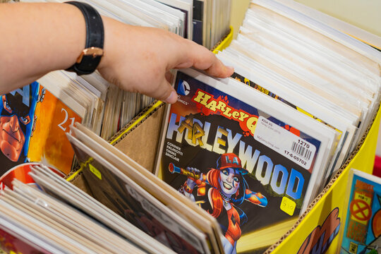 8th Comic Con  Convention In GUAYAQUIL, ECUADOR - AUG 06, 2023 - Woman's hand selecting comics from a box. Comic shop with many copies.