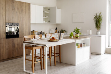 Interior of modern kitchen with island table served for dinner