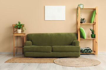 Interior of living room with cozy green sofa, shelving unit and houseplants