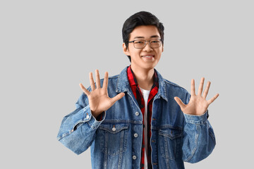 Young Asian man showing ten fingers on light background