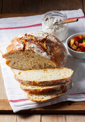 Round yeast bread made from white and whole grain flour, tomato salad and pate on a wooden background. Rustic style.