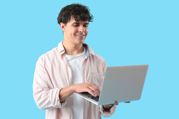 Male programmer working with laptop on blue background