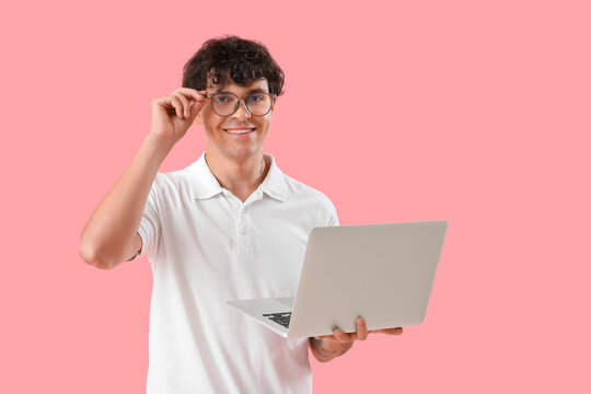 Male programmer with laptop on pink background