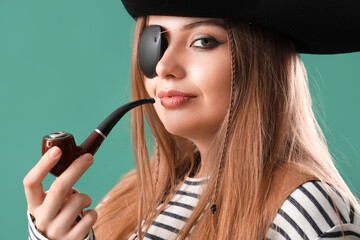 Beautiful female pirate smoking pipe on green background