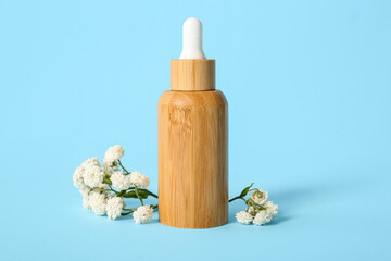 Bottle of essential oil and gypsophila flowers on color background