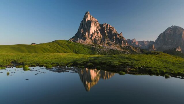 Passo Giau italian Dolomites slow flyover over water or lake with mountain view and its reflection in the water and beautiful green mountain meadows
