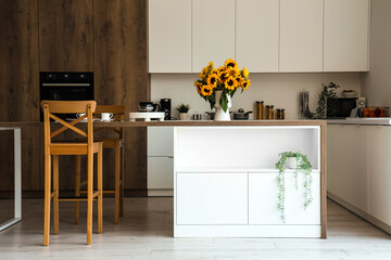 Interior of modern kitchen with sunflowers in vase on table