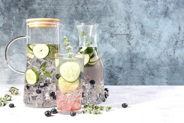 Detox fruit flavored water with cucumber and mint on a dark background. Refreshing summer homemade lemonade cocktail. Fruit juice and ingredients, weight loss concept, healthy and natural food,
