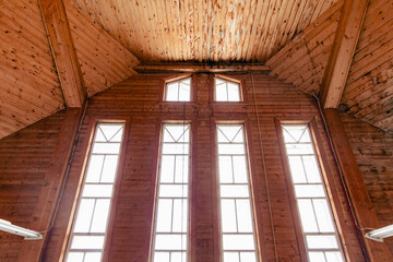 Fototapeta na wymiar vue sur un mur en latte de bois avec de grandes fenêtres verticales et un plafond en bois avec de la lumière naturelle