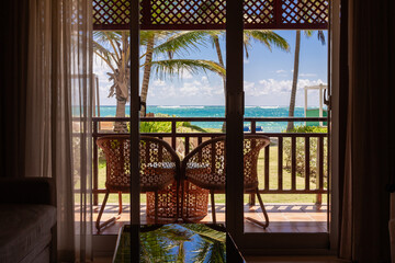 vue sur un balcon avec des chaises extérieur avec vue sur la mer et un palmier lors d'une journée ensoleillée