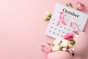 Early detection campaign setup. Top view of october calendar with pink ribbon, bra and eustoma...