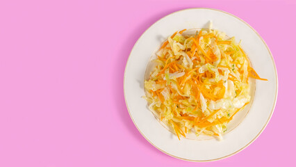 Plate of coleslaw over pink background with copy space.