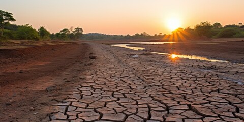 The sun is setting over a dry river bed. AI.