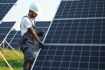 An Indian male worker is working on installing solar panels in a field