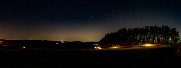 A panoramic view of the night sky over longnor wood in the English Peak District.