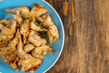 Roasted turkey pieces on ceramic plate over wooden background.