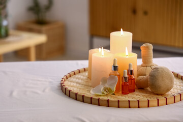 Burning candles, oil and herbal bags on table in spa salon