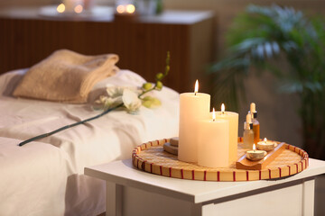 Burning candles and essential oil on table in spa salon