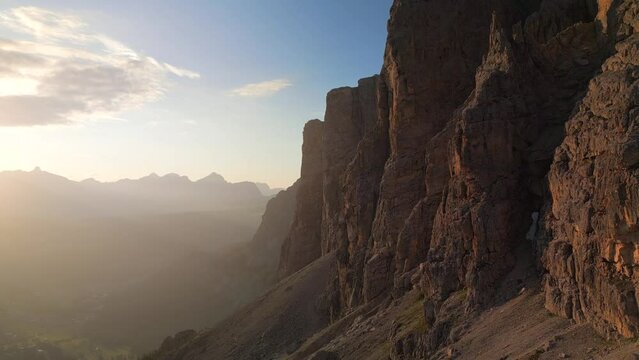 Aerial flight adove the stunning Alps. High mountain peaks sharp cliffs Dolomites, Italy. Fly past a beautiful cliff at sunset
