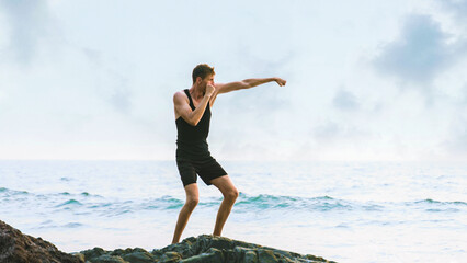 young man is conducting boxing training sessions on the beach by the sea