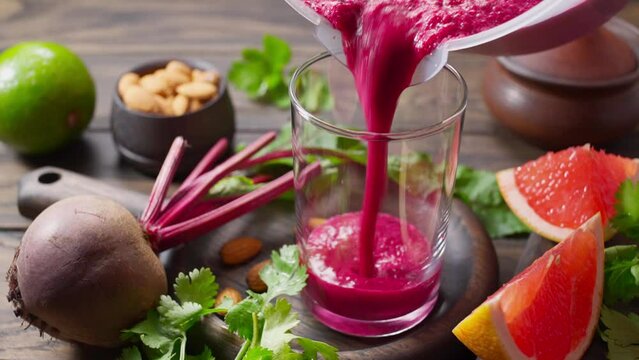 Pouring detox drink from beetroot and grapefruit into glass. Colon cleansing smoothie