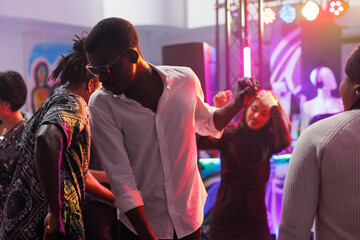 African american clubber in sunglasses partying on crowded dancefloor at nightclub discotheque....