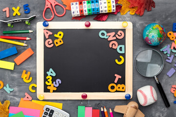 School board with alphabet and school supplies on a gray table. View from above. Space for text. The concept of school education.