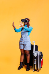 Modern girl using vr headset on holiday, carrying suitcase bags and using virtual reality glasses. Young tourist having fun with artificial intelligence 3d goggles, travelling on vacation.