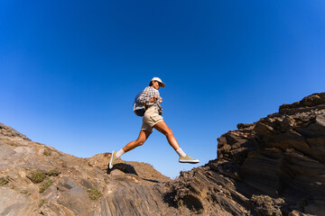 tourist girl with a backpack on her back climbs the mountain in summer