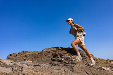tourist girl with a backpack on her back climbs the mountain in summer