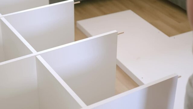 assembling cabinet furniture parts at home, male hands close-up, master, handyman services, showcasing skills handyman, DIY enthusiast working on furniture assembly and home improvement tasks