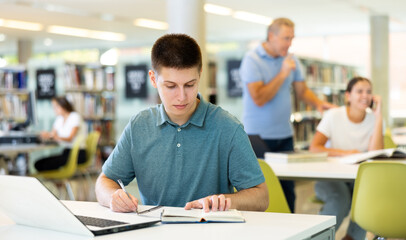 Fototapeta na wymiar Smart male student preparing for the exam in the school library