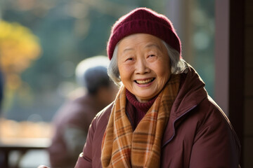 Elderly asian woman smiling, sitting in a park cafe