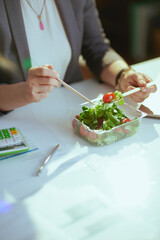 Obraz na płótnie Canvas Modern woman employee in green office eating salad