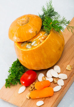 Image of tasty homemade pumpkin soup puree served in pumpkin at wooden desk