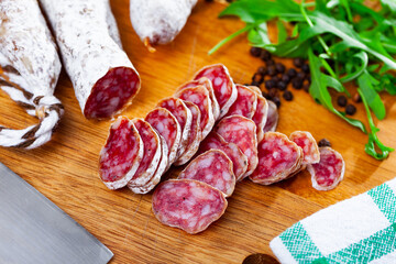 Fuet, traditional spanish smoked pork salami on a wooden kitchen board