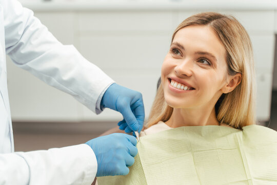 Portrait of smiling beautiful female patient with blond hair sitting in dental chair. Dental care