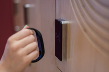 A woman opens the electronic lock of a cubicle in a locker room with a bracelet. 