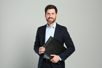 Handsome real estate agent with documents on grey background