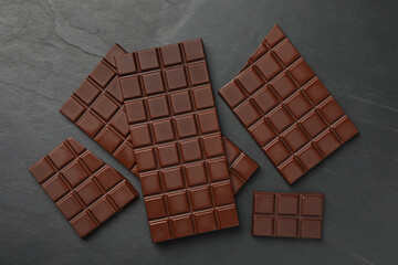 Pieces of tasty chocolate bars on grey table, flat lay