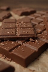 Pieces and crumbs of tasty chocolate bars on parchment paper, closeup