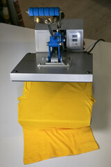 Printing logo. Heat press with yellow t-shirt on white table