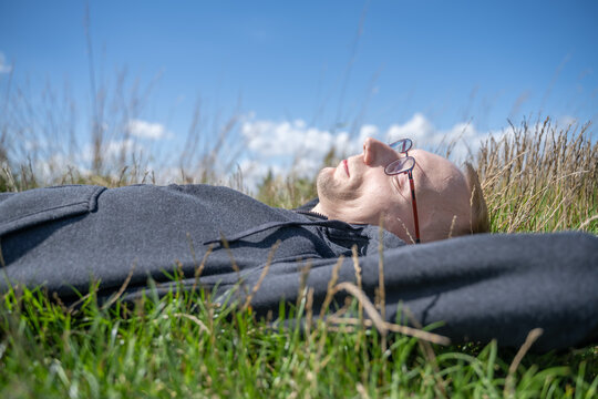 jeune homme blond allong&eacute; dans l'herbe au soleil