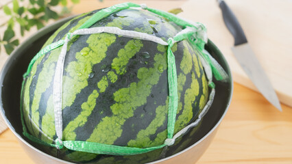 紐で縛ったスイカ｜水の入ったボウルにつける