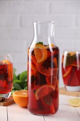 Delicious punch drink and slices of fruits on white wooden table