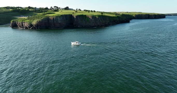 Motorboat travelling along the rocky cliff bank entering the bay 4k